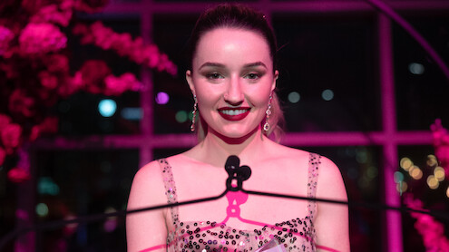 Kaitlyn Dever as Belle smiles at a podium in 'Apple Cider Vinegar'