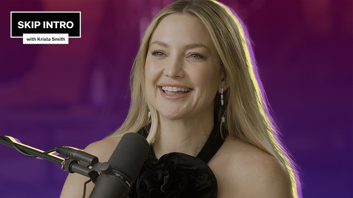 Kate Hudson is smiling as she sits in front of a microphone.