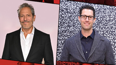 Two men in suits pose separately against different backdrops; the man on the left stands before a plain light background, while the man on the right stands in front of a patterned black and white wall. Both are smiling and appear at a formal event.