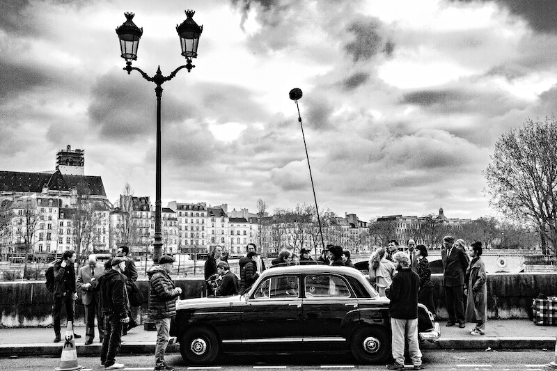Cast and crew film Nouvelle Vague in the streets of Paris.