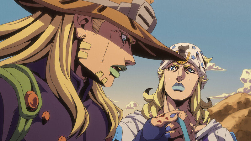 Two animated characters with long blond hair, distinctive hats, and outfits stand outdoors in a desert landscape, engaged in conversation under a clear sky with mountains in the background.