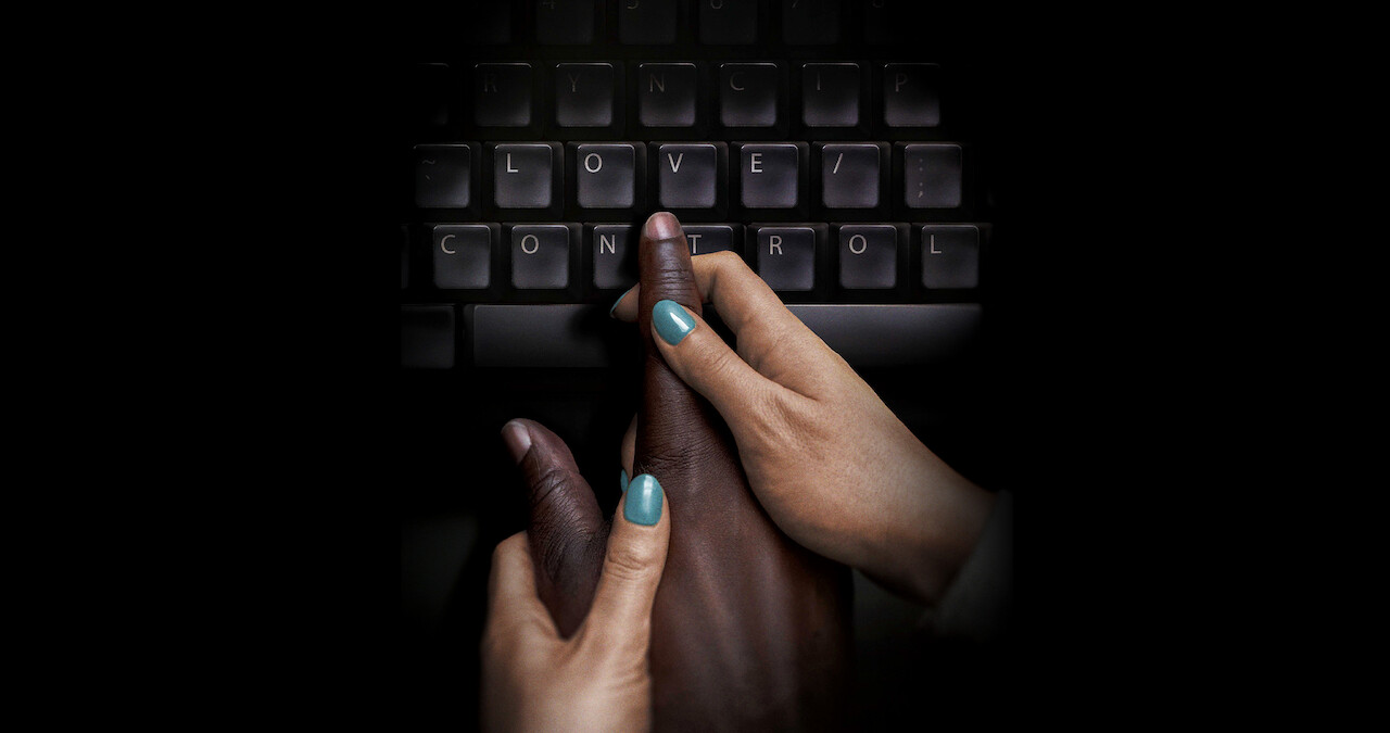 Hands guiding a hand to type on a keyboard.