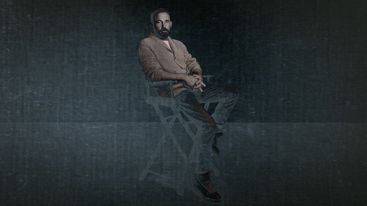 A black and white photo of Ben Affleck sitting in a director's chair on a seamless backdrop looking to camera with his hands in his lap. The photo has a grainy texture applied over top for a stylized treatment.