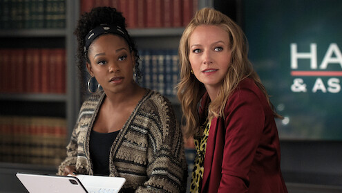 Two women standing together behind a desk.