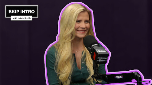 Elizabeth Smart sits smiling in front of a microphone during a podcast recording for "Skip Intro with Krista Smith." The background is purple, and the podcast logo appears in the top left corner.