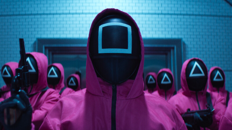 A group of people in pink hooded jumpsuits and masks gathered in Season 2 of 'Squid Game'