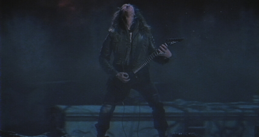 Eddie Munson playing guitar in a night scene.