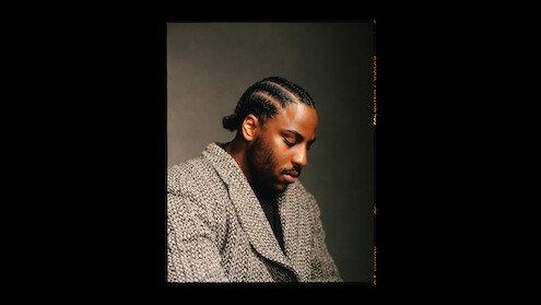 Malcolm Washington wears a patterned coat and sits in profile.