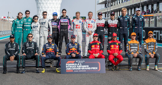 Formula 1 race car drivers pose for a photo with Abu Dhabi Grand Prix sign