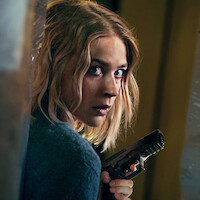 Jeanne Goursand holds a gun as she peeks around a corner in an image from the film 'Exterritorial.