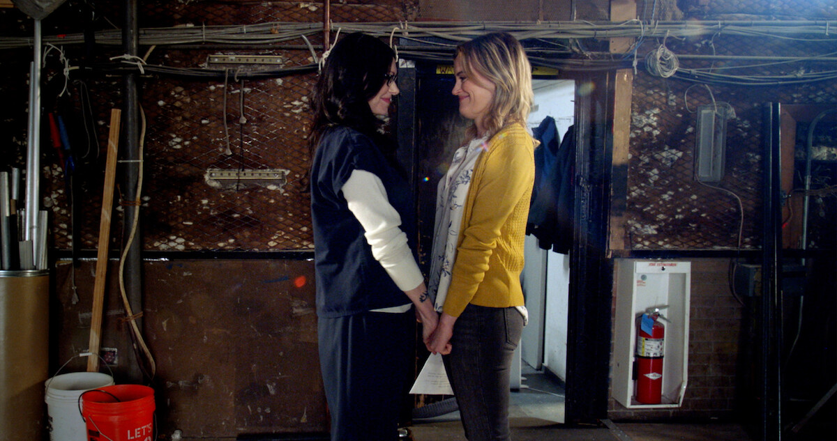 Taylor Schilling as Laura Prepon holding hands.