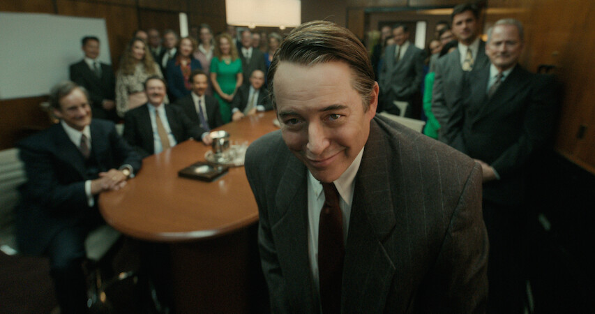 Matthew Broderick as Richard Sackler slyly smiles to the camera with a conference room full of employees standing behind him in Season 1 of 'Painkiller.'  