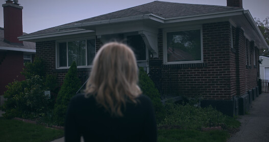 A woman in the foreground looks at a house.