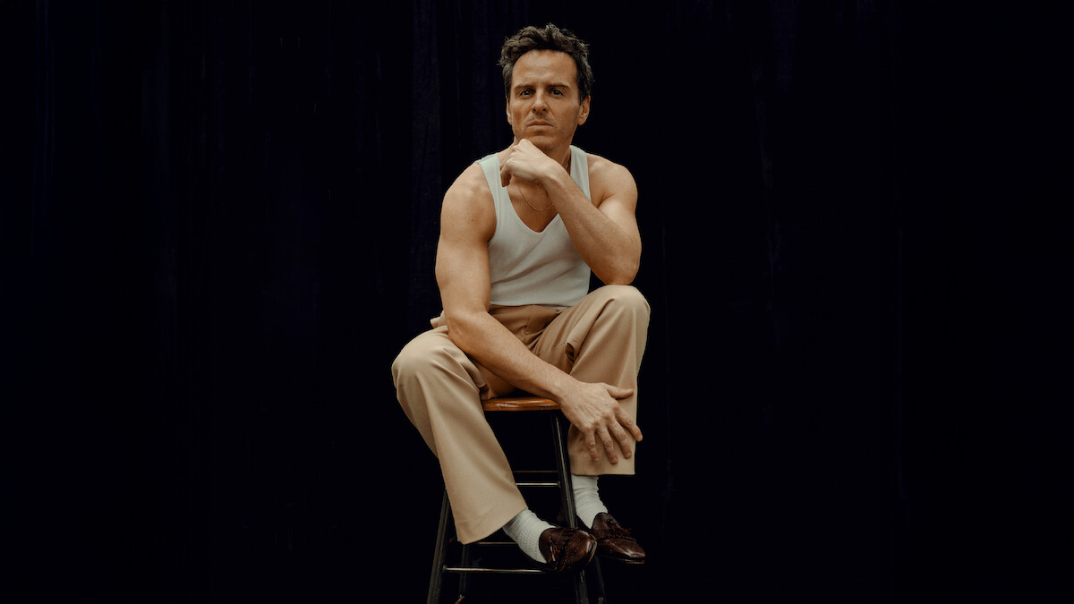 Andrew Scott wears khakis, a white tank, loafers, and a blazer or coat draped over his shoulders.