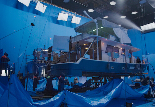 Um set de filmagem tem cores predominantemente azuis e um grande barco no meio, sobre uma plataforma móvel